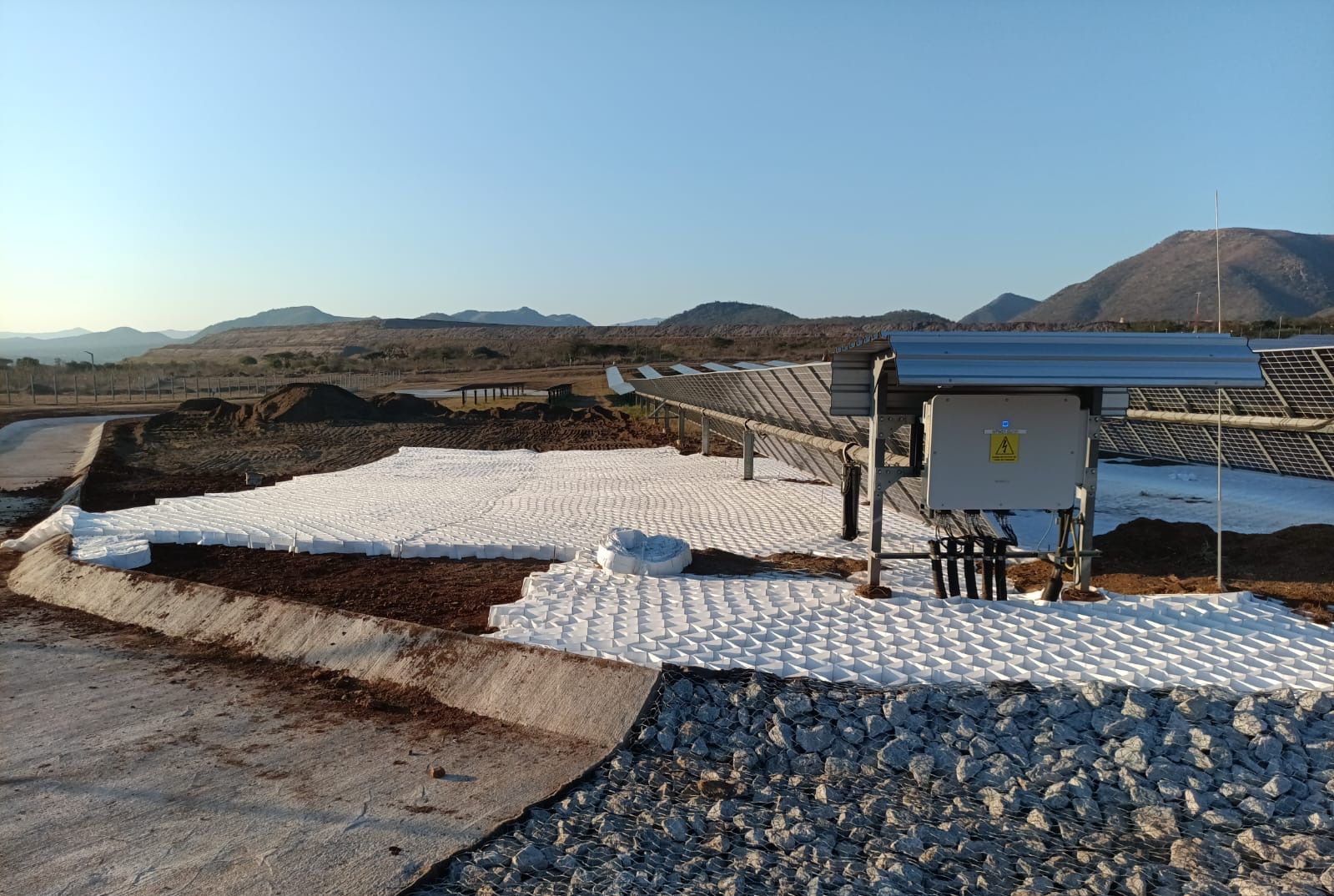 Greencell / Multicell panels on geotextile, with a gabion apron, beside a solar inverter at Balfour