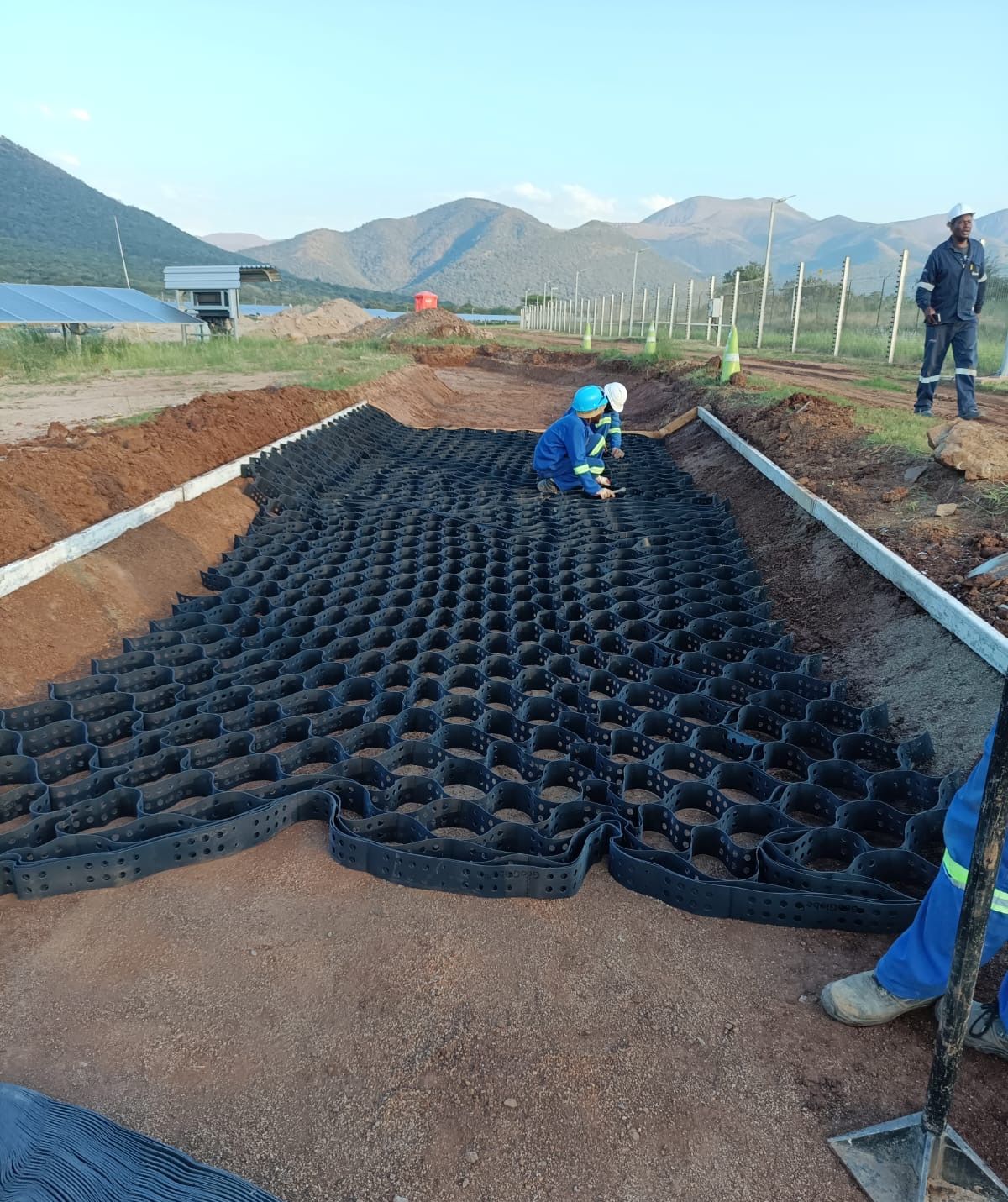 Crew opening Greencell / Multicell panels in a channel beside the solar panels at Balfour, with mountains behind